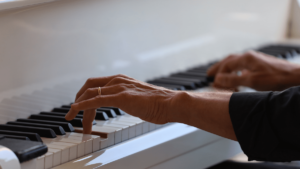 Close-up of elderly hands playing the piano, symbolising remembrance through music for the older generation's funeral songs
